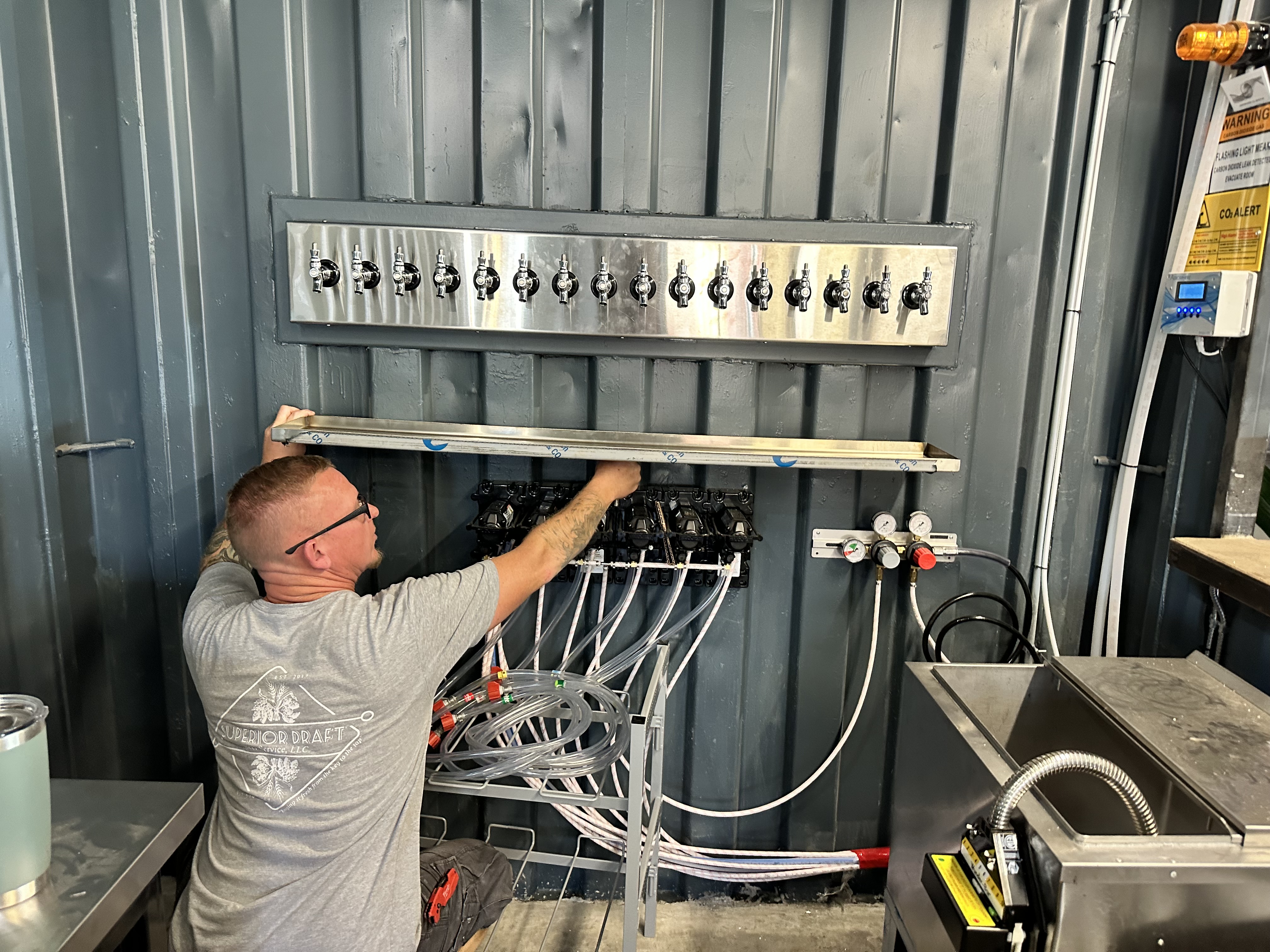 Technician installing a 14-tap wall-mounted draft system